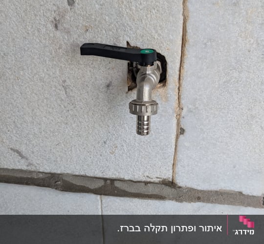 ברז מים מותקן על קיר בטון